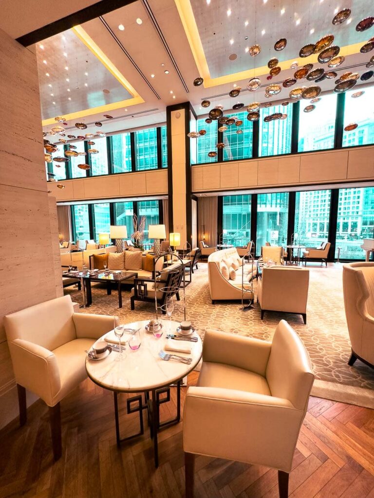 A warm seating area with chairs, sofas, and coffee tables with a view of the city, Pavilion, The Langham Hotel, Chicago